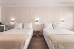 A hotel room with two beds, wooden panel walls, and bedside lamps.