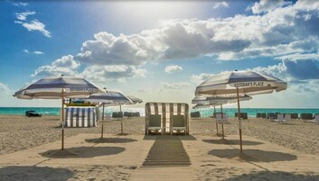 Perto da praia, areia branca, espreguiçadeiras, toalhas de praia 