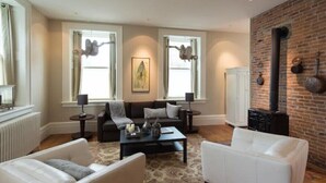 A living room with a sofa, two white armchairs, a coffee table, and a fireplace. - Capitan Burn's House on Wellington
 (Kingston)