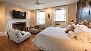A bedroom with a fireplace, a television, a bed, a sofa, and a large painting on the wall. - Capitan Burn's House on Wellington
 (Kingston)