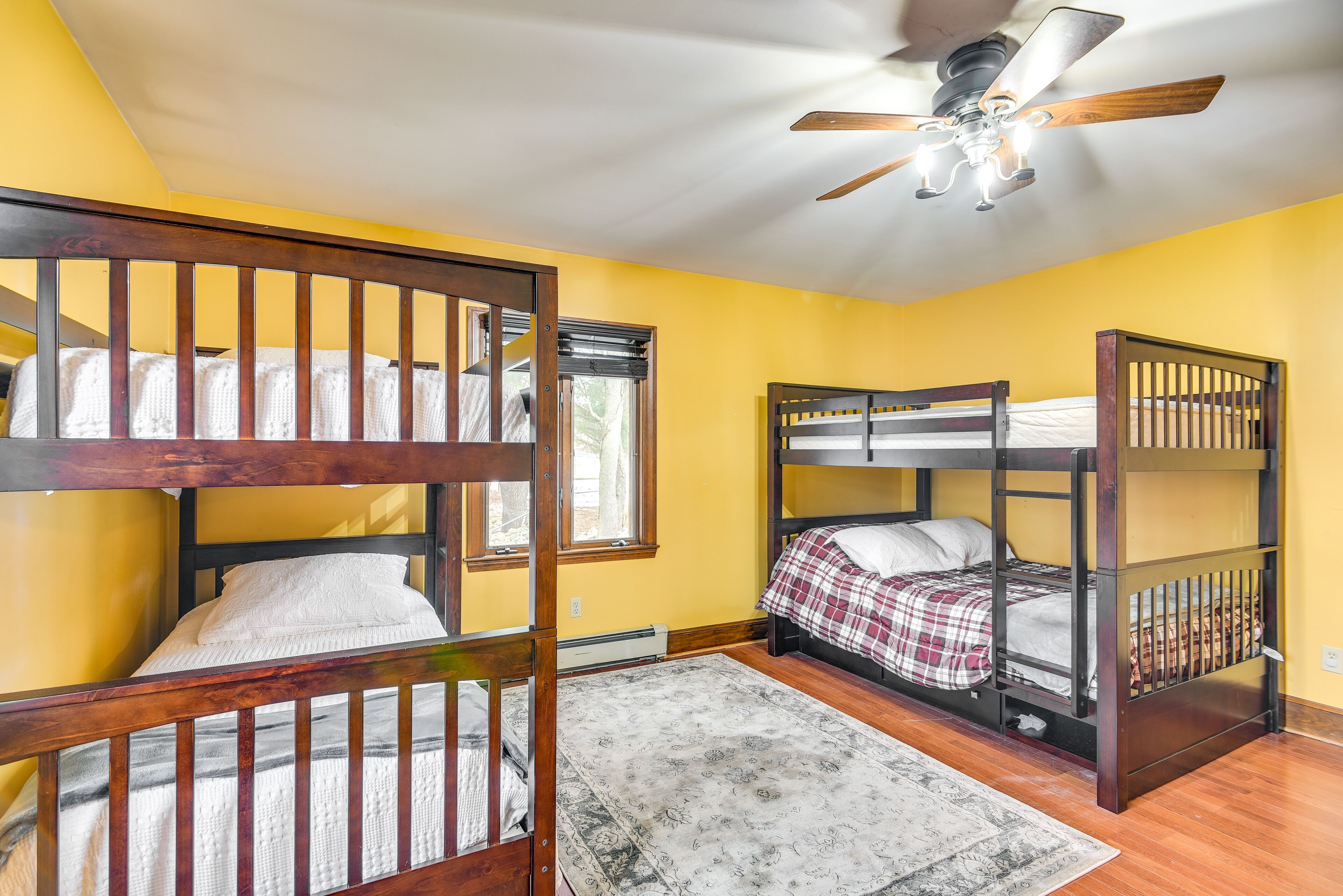 A room with three bunk beds, a ceiling fan, and a window.