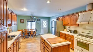 Una cocina con armarios de madera, una isla central, una estufa y un refrigerador.