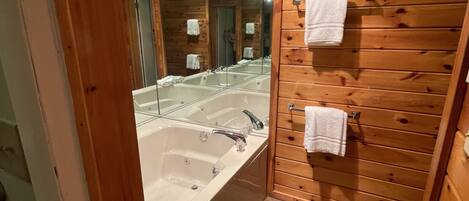 Un baño con pared de madera, un espejo grande y dos lavamanos.