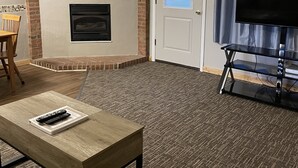 A living room with a fireplace, a television, and a dining area with a table and chairs. - Endless Mountain Resort (Union Dale)