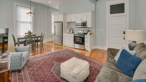 Una sala de estar moderna con un sofá, un reposapiés y un comedor con sillas y una mesa.