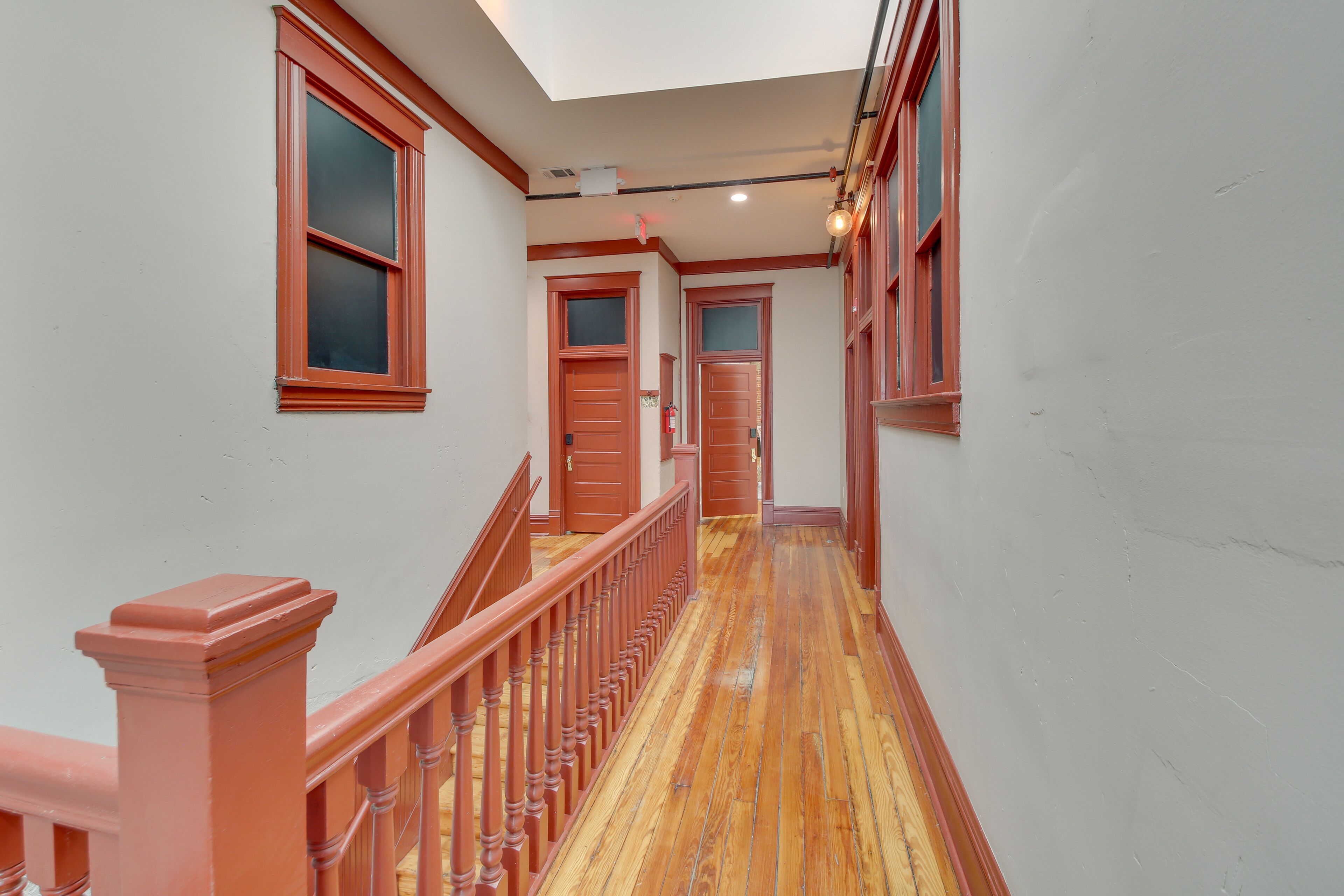 A hallway with wooden floors and red trim, leading to multiple doors.