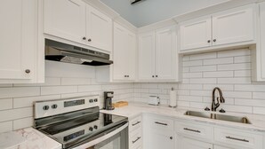 A modern kitchen with white cabinetry, a stainless steel range, and a built-in oven. - Downtown Hot Springs Condo Near Bathhouse Row! (Hot Springs)
