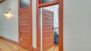 Un couloir doté d’un plancher en bois et de deux portes marron fermées, ornées de panneaux de verre.