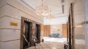 A hotel lobby with marble flooring, two elevators, a reception desk, and chandeliers. - Lamar Ajyad First Hotel Tower B (Makkah)