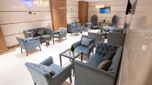 A modern lounge area with multiple seating options including sofas and armchairs, a glass coffee table, and decorative lighting. - Lamar Ajyad First Hotel Tower B (Makkah)