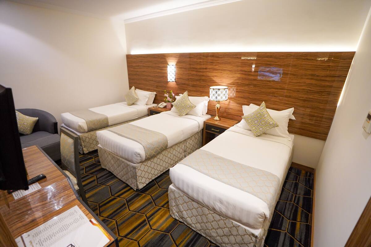 A hotel room with two single beds, a desk with a computer, and a small seating area.