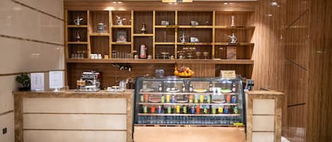 A coffee shop with a wooden interior, a glass display case with beverages, and shelves with coffee-related items.