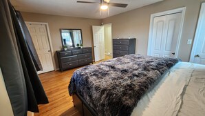 Een slaapkamer met een bed, een dressoir, een spiegel en een plafondventilator.