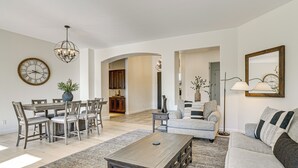 Ein geräumiges Wohnzimmer mit Essbereich, einer Couch, einem Couchtisch und einem Kronleuchter.