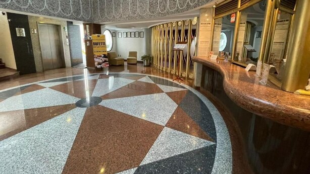 Un hall d’entrée avec un sol à carreaux, un comptoir d’accueil et un grand miroir.
