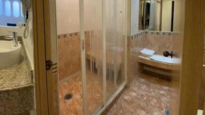 Une salle de bain moderne dotée d’une douche à parois de verre, d’un lavabo avec un plan de travail en marbre et d’un miroir au-dessus du lavabo.