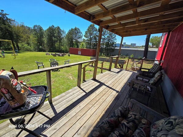A wooden deck with outdoor furniture, a grill, and a view of a grassy yard with trees. - Papas Cabin- block away from lake & Lacys marina. Property has Rv & boat parking (Higden)