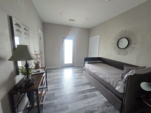 A hotel room with a bed, a desk, a lamp, a mirror, and a door. - Papas Cabin- block away from lake & Lacys marina. Property has Rv & boat parking (Higden)