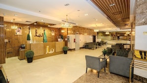 Um saguão de hotel com balcão de recepção, área de estar e escadaria.