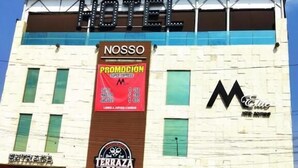 Een hotel met een opvallend 'HOTEL'-bord, 'NOSSO'-branding, een 'PROMOCIÓN'-bord en een 'TERRAZA BAR'-bord.