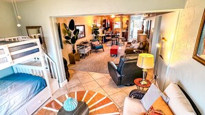 A room with a bunk bed, a round coffee table, a sofa, and a dining area with chairs and a table. - Good Vibrations- Stay right ON the beach in Siesta Key! Sleeps 6 (Siesta Key)