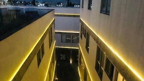 A corridor with yellow lighting, a number 26 sign, and a view of the city at dusk. - HOTEL M DORADO (Mexico City)