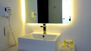 A bathroom with a white sink, a large mirror, and a hairdryer on the wall. - HOTEL M DORADO (Mexico City)