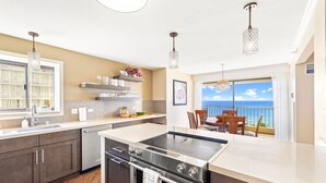 A modern kitchen with a large island, stainless steel appliances, and a view to the outside. - Oceanfront Condo W Free Valet Parking & Balcony (Honolulu)