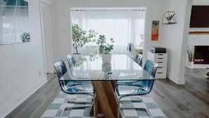 A modern dining area with a glass table, blue chairs, and a checkered floor.