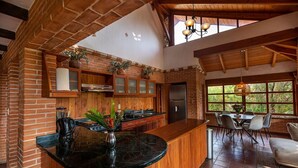 Cozinha moderna com ilha central, armários de madeira e uma grande janela com vista para o verde.