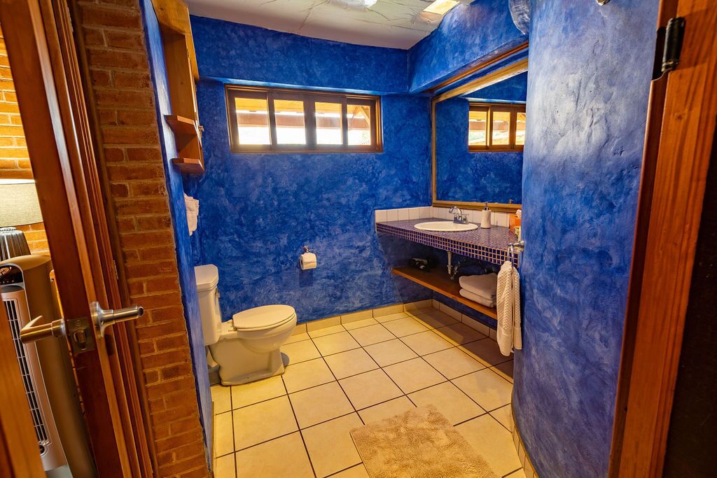A bathroom with a blue wall, a white toilet, a sink, and a mirror.