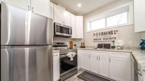 A modern kitchen with stainless steel appliances, white cabinetry, and a sign advertising baking products. - NEW - Mountain Chic Escape - Whyte Ave - Netflix - Clean!
 (Edmonton)