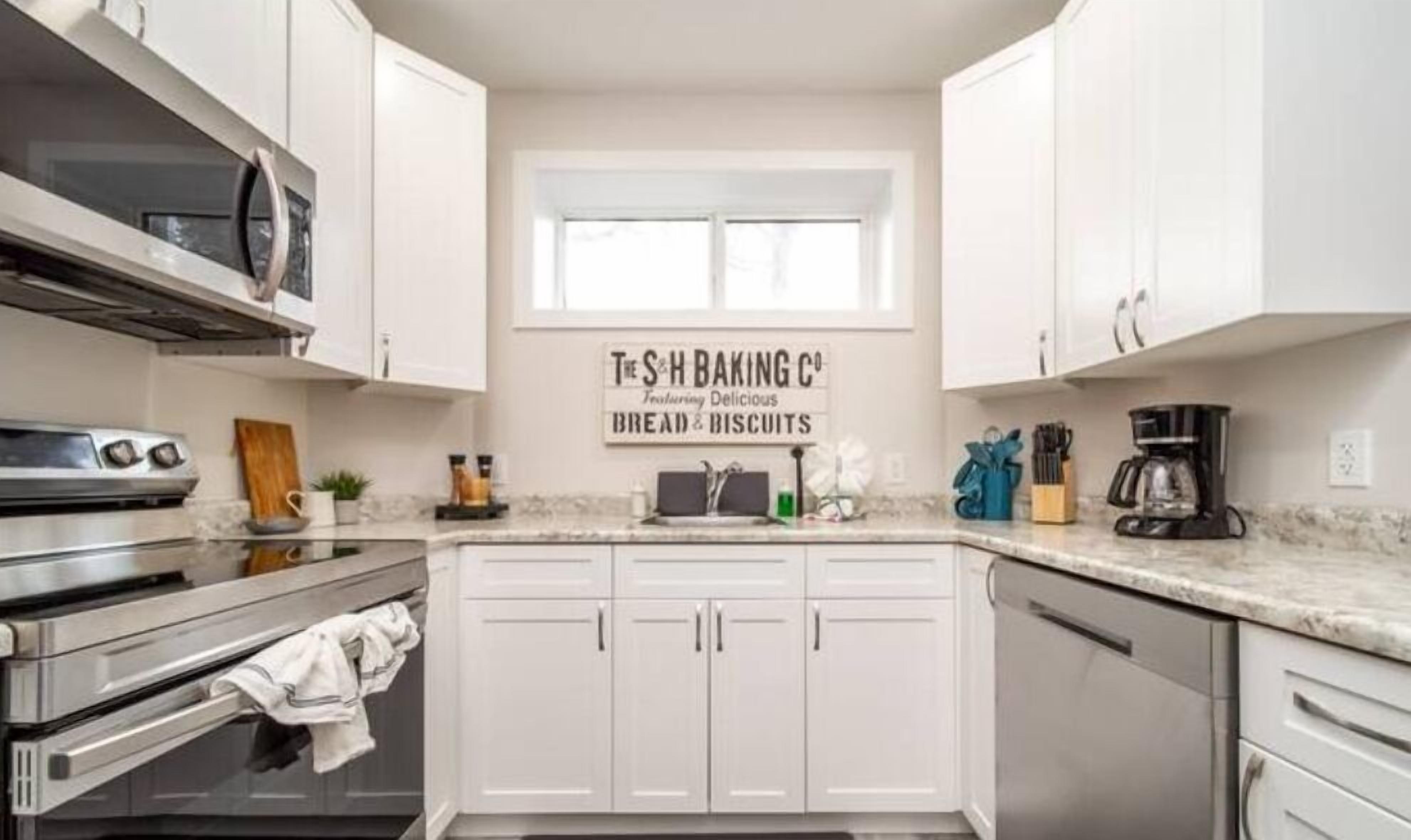A kitchen with white cabinets, a stainless steel oven, a coffee maker, and a sign advertising 'The S&H Baking Co.'