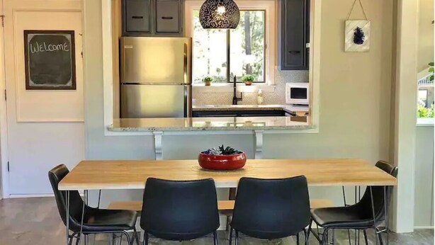 A modern kitchen with a built-in island, stainless steel appliances, and black chairs around a wooden table.