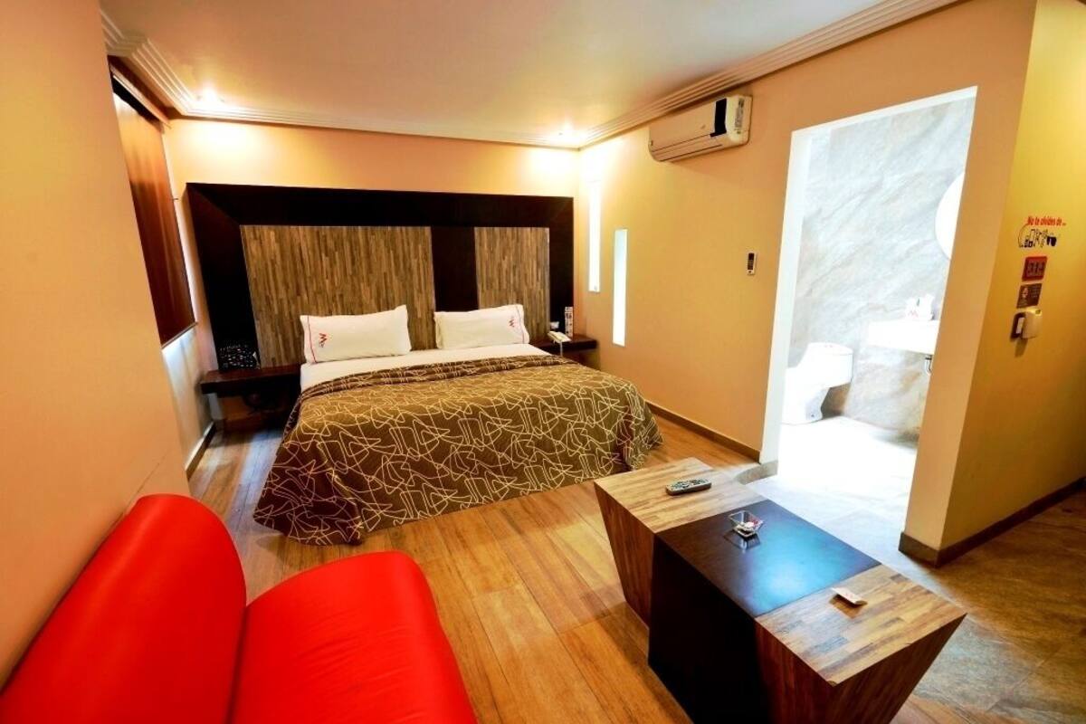 Une chambre d’hôtel avec un lit, un bureau et une chaise rouge.