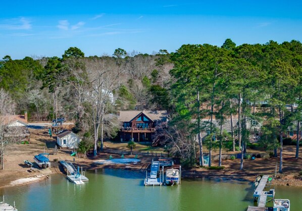 A lakeside property with a dock, boats, and a cabin.
