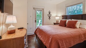 Une chambre à coucher avec un lit, des lampes de chevet, une télévision et un ventilateur de plafond.