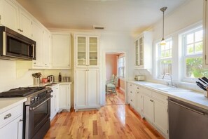Una cucina con mobili bianchi, un forno a microonde, un fornello e un lavandino.