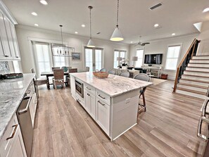 A spacious kitchen with a large island, wooden flooring, and modern appliances. - Welcome to Paradise - MUST SEE Brand New Luxury Home (Orange Beach)