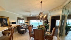 Ein geräumiges Wohnzimmer mit einer Kronleuchter, einem Essbereich mit Holzsesseln, einem Sofa und einem Fernseher.