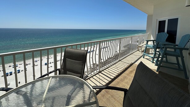 A balcony with a view of the beach and ocean. There are chairs and a table on the balcony. - 1303 is a beautiful 2br/2ba 13th floor unit with a magnificent view! (Panama City Beach)