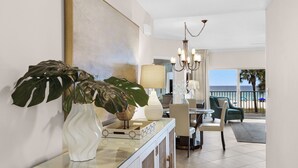 A hotel lobby with a glass coffee table, a white vase, and large green plants. There is a chandelier and a view of the beach through the windows. - 2nd fl. 2 br newly remodeled unit with Stunning Views! Beach chairs included! (Panama City Beach)