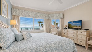 A bedroom with a large bed, a television, a dresser, and a ceiling fan. - 2nd fl. 2 br newly remodeled unit with Stunning Views! Beach chairs included! (Panama City Beach)