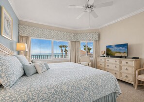 A bedroom with a large bed, a television, a dresser, and a ceiling fan.