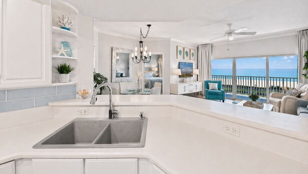 A modern kitchen with a double sink, a chandelier, and a view of the ocean. - 2nd fl. 2 br newly remodeled unit with Stunning Views! Beach chairs included! (Panama City Beach)