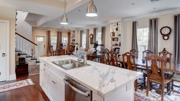 A spacious kitchen with a marble island, wooden dining table, and chairs. - Grey Mist Modern 3bd 2ba on Quiet Street (West Palm Beach)