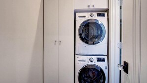 A laundry room with two stacked washing machines and a closed wardrobe. - Grey Mist Modern 3bd 2ba on Quiet Street (West Palm Beach)