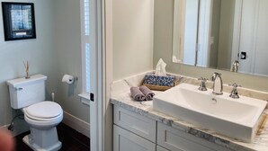 A bathroom with a toilet, sink, and mirror. - Grey Mist Modern 3bd 2ba on Quiet Street (West Palm Beach)