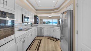 A modern kitchen with white cabinetry, stainless steel appliances, and a view to the outside. - Beachfront 2br/2ba condo on the 3rd floor with free beach chairs included! (Panama City Beach)