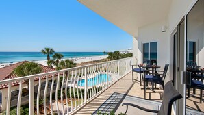 A balcony with a pool, chairs, and a view of the beach and ocean. - Beachfront 2br/2ba condo on the 3rd floor with free beach chairs included! (Panama City Beach)